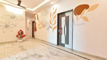 Een hotel lobby met een modern design, met een receptiebalie, een wand met bloemkunst en een welkomstbord.