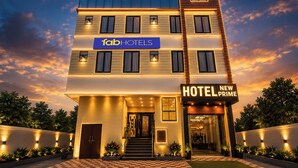 Un hotel de varios pisos con fachada moderna, un cartel llamativo para 'fabHOTELS' y un letrero que indica 'HOTEL NEW PRIME'.