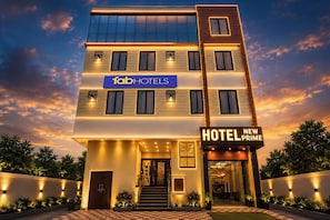 Un hôtel à plusieurs étages, doté d’une façade moderne, d’une enseigne bien visible pour « fabHOTELS » et d’une autre pour « HOTEL NEW PRIME ».