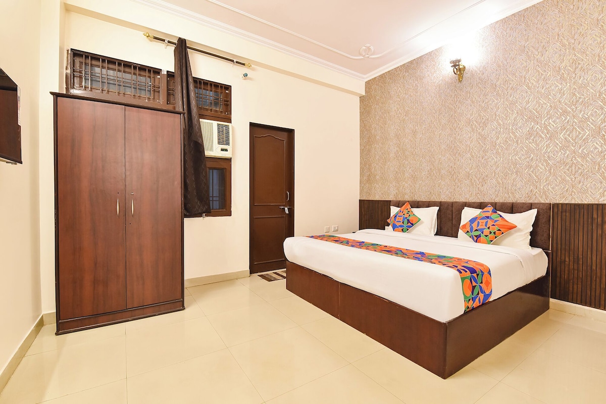 Une chambre d’hôtel avec un grand lit, une armoire et une fenêtre équipée d’un climatiseur.