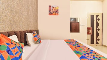 Habitación de hotel con cama, almohadas, un cuadro en la pared, armario y una puerta con un cartel que dice 'Gracias'.