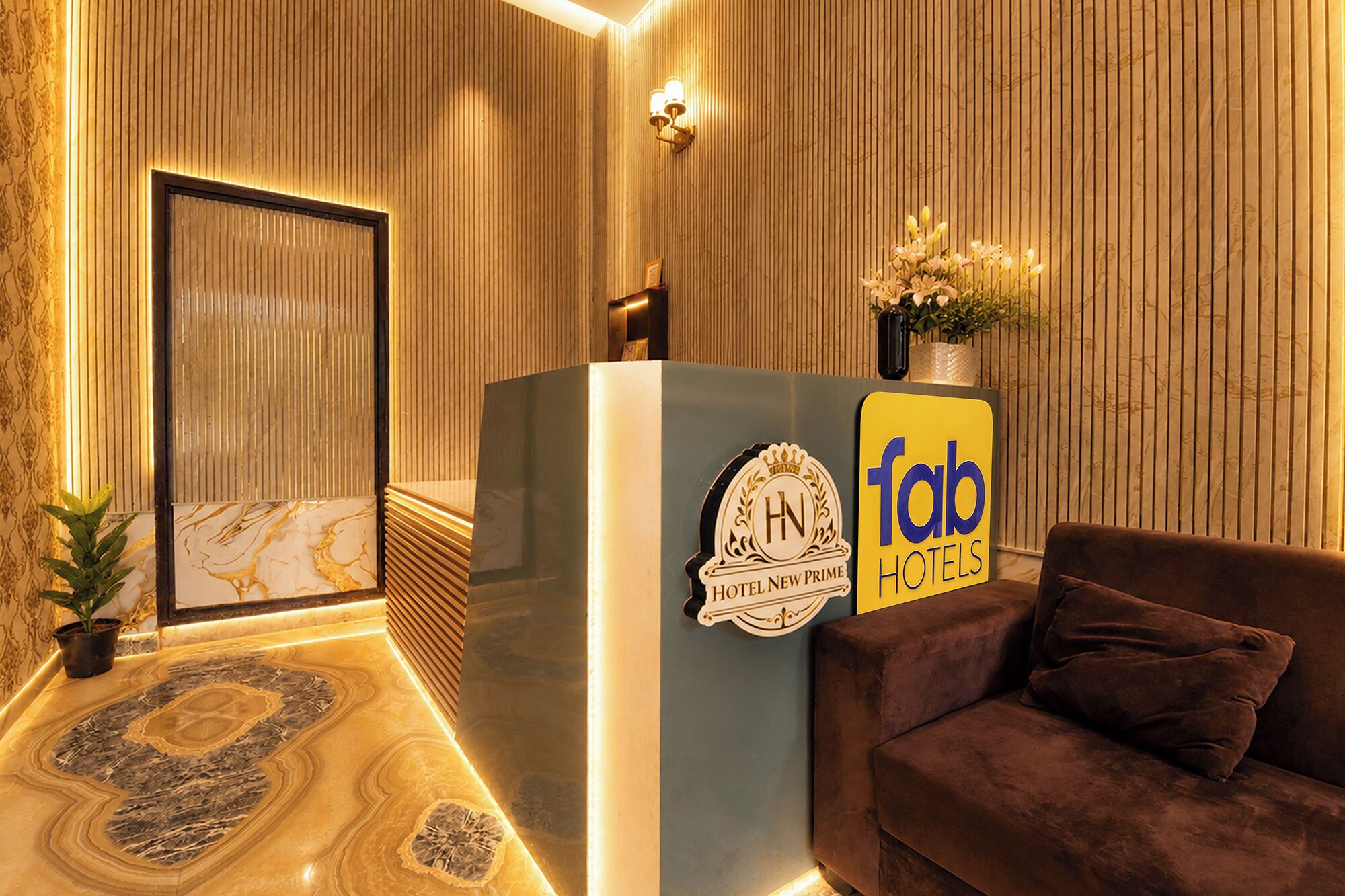 A reception desk with a logo, a sofa, and a wall with vertical lines.