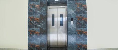 An elevator with a metallic finish and a control panel on the right side.