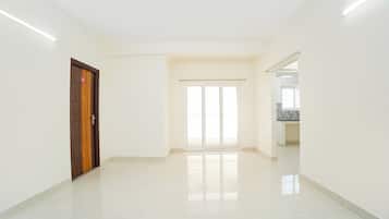 A spacious, well-lit hallway with a wooden door and a sliding glass door leading to a balcony.