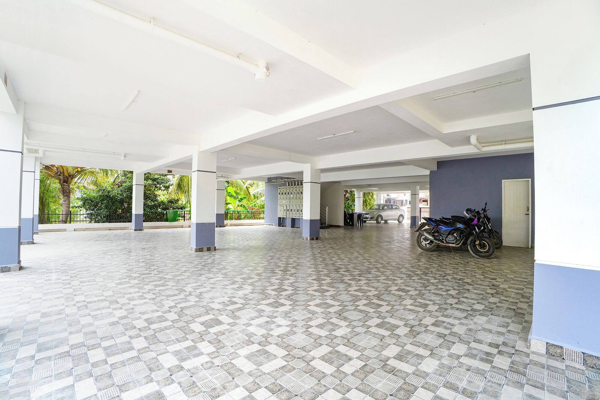 A spacious indoor area with a tiled floor and a motorcycle parked near a wall.