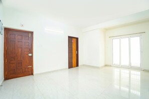 Una habitación amplia y vacía, con dos puertas de madera y un gran ventanal.