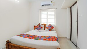 Un dormitorio con cama, ventana, aire acondicionado y puerta.