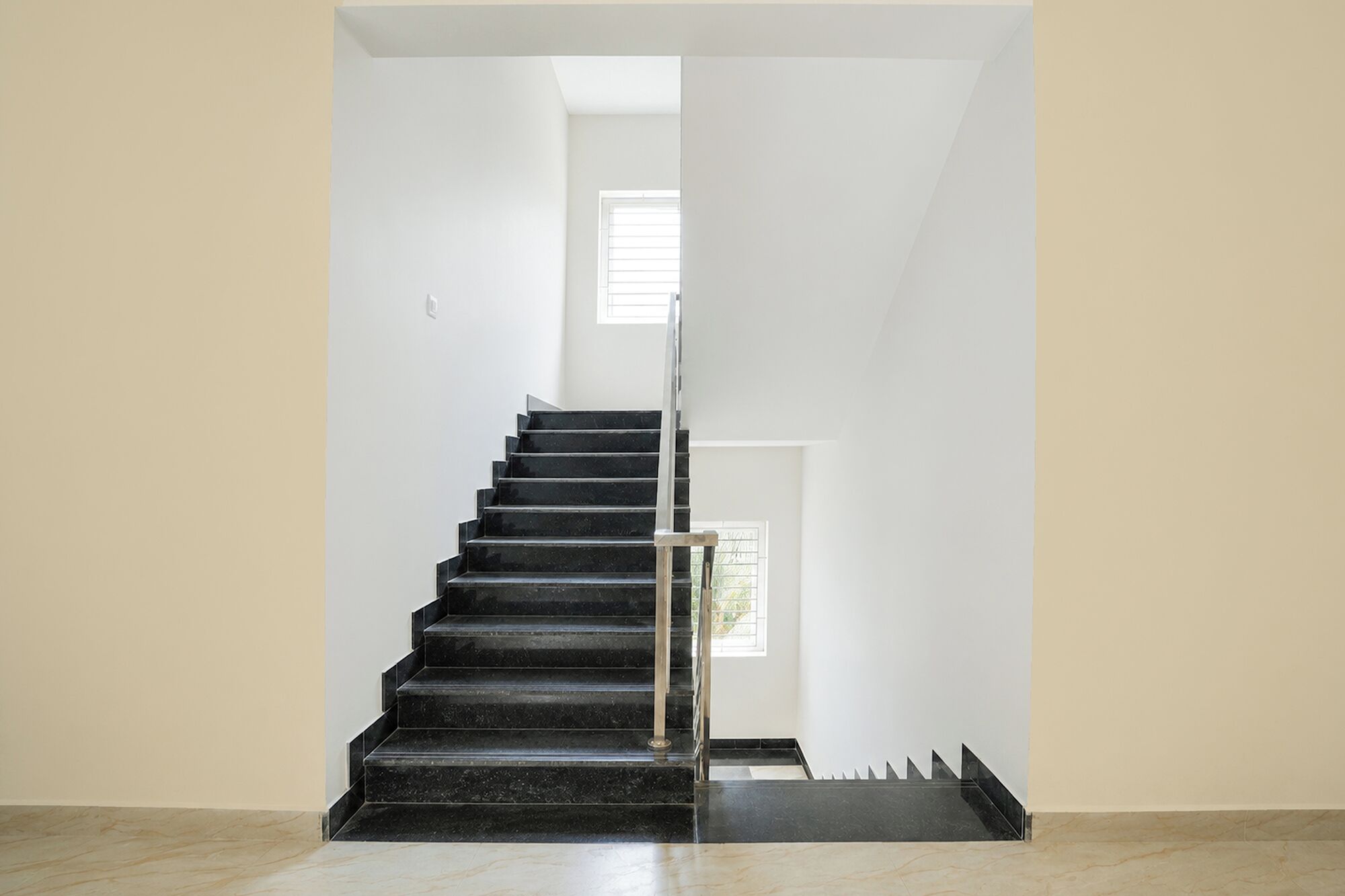 A modern staircase with a glass railing, leading to a bright room with a window.