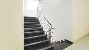 Un escalier avec des marches noires et une rampe métallique menant à un palier.