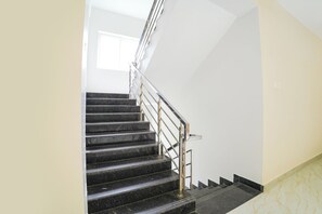 Una escalera con peldaños negros y barandilla metálica que conduce a una plataforma.