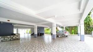 Un área de estacionamiento techada con piso de baldosas, un coche y una escalera que lleva a un nivel superior.