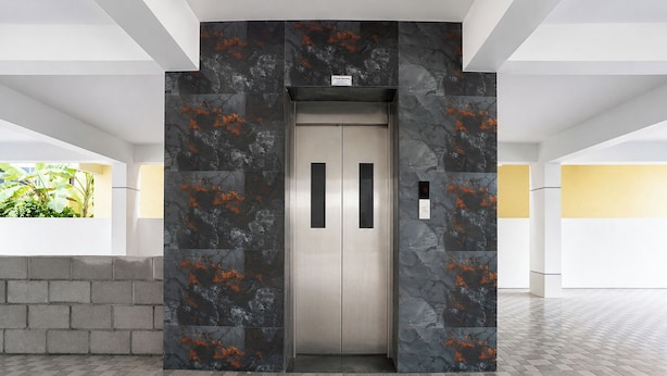 Un ascensor con diseño de pared de mármol, panel de control y techo transparente.
