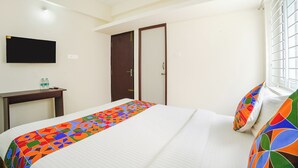 Une chambre d’hôtel avec un lit, un bureau, une télévision et une porte.