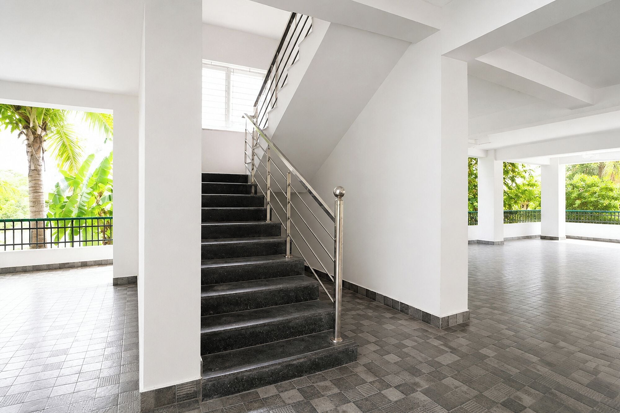 A staircase with metal railings leading to an upper floor, surrounded by white walls and a tiled floor.