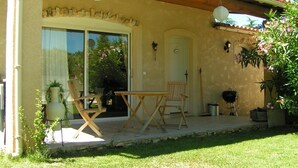 A covered patio with a table and chairs, a door, and potted plants. - Little butterfly (Carpentras)