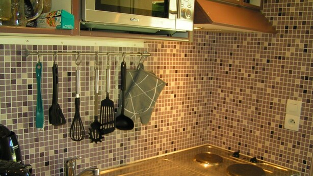 A kitchen with a stainless steel sink, a microwave, and various utensils hanging on the wall. - Little butterfly (Carpentras)