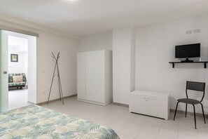 A bedroom with a bed, a wardrobe, a desk, a chair, and a television on a stand. - Dinologo Modern Flat by Wonderful Italy (Siracusa)