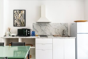A modern kitchen with a marble backsplash, a microwave, a sink, and a refrigerator. - Dinologo Modern Flat by Wonderful Italy (Siracusa)