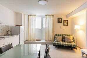 A modern kitchen with a dining table and chairs, a sofa with cushions, and a floor lamp. - Dinologo Modern Flat by Wonderful Italy (Siracusa)