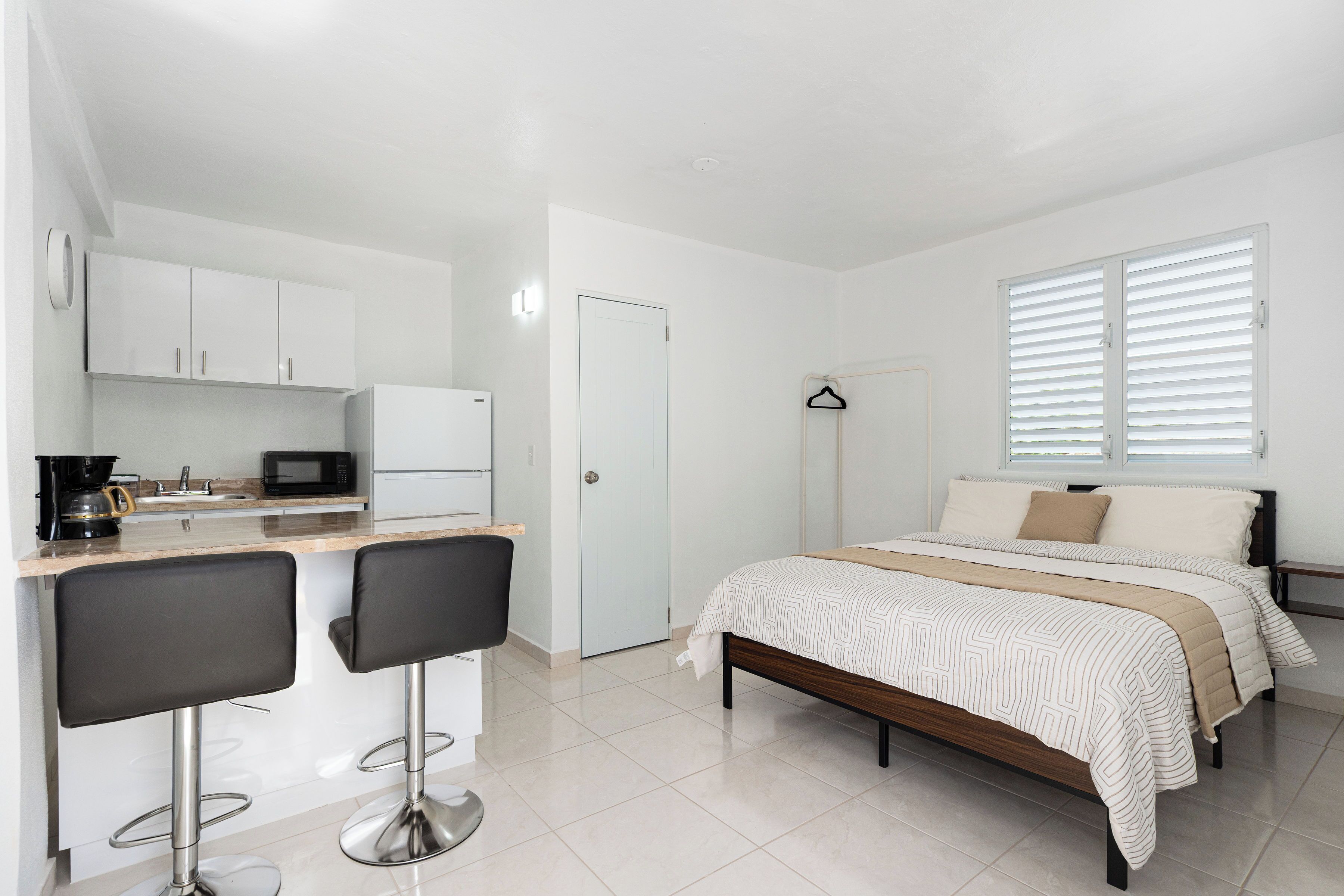 Une chambre à coucher de taille modeste, comprenant un lit, une table de chevet et une fenêtre avec des stores.