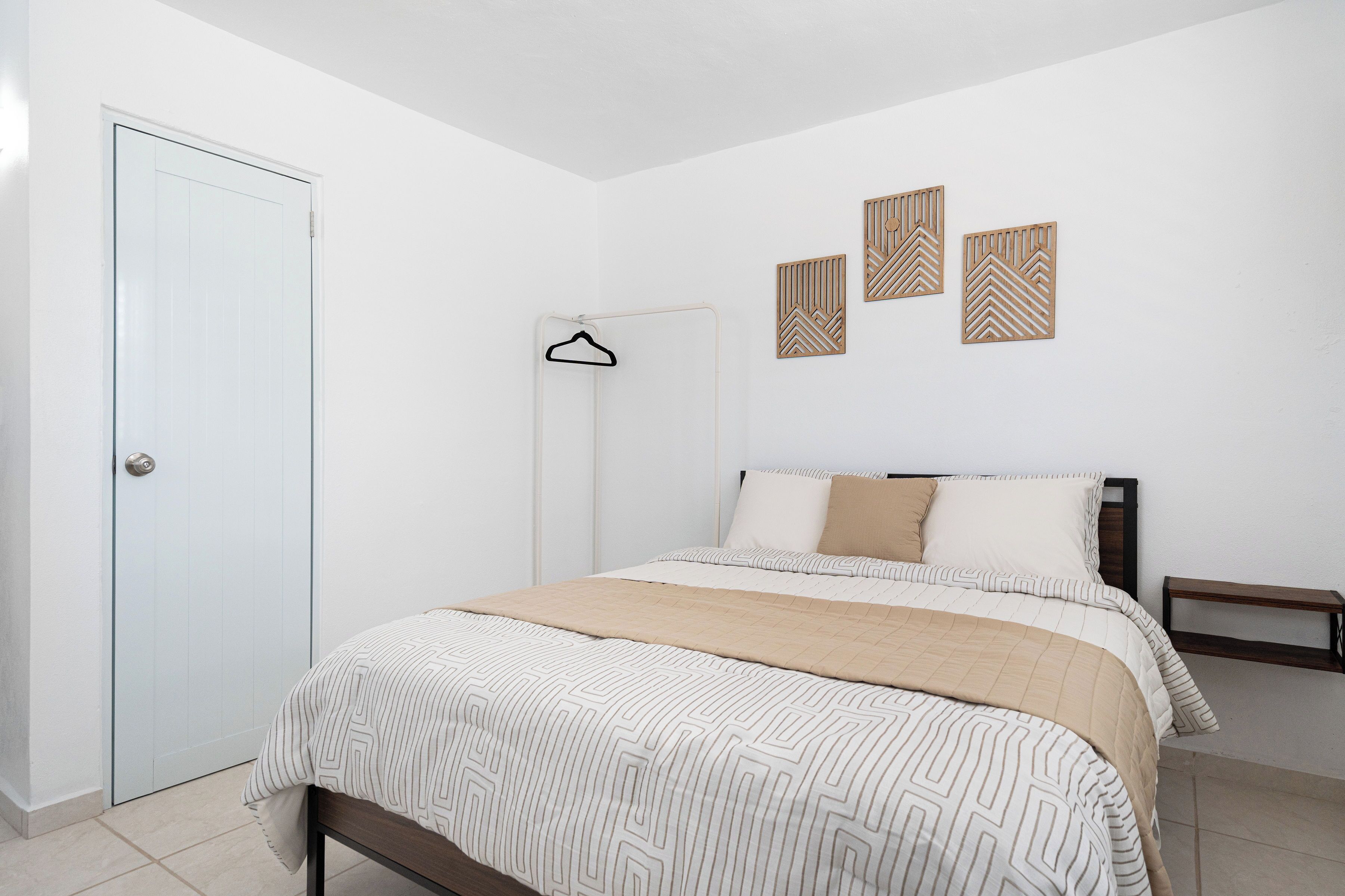 Un dormitorio con cama, armario, banco y decoración en la pared.