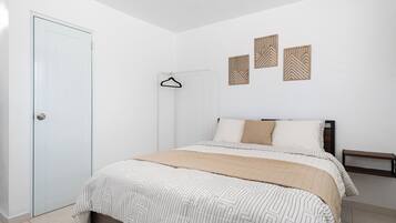 Un dormitorio con cama, armario, banco y decoración en la pared.