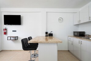 Una cocina moderna con televisor de pantalla plana, cafetera y un reloj en la pared.