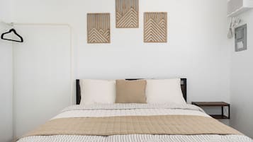 Un dormitorio con una cama, perchero y tres paneles decorativos en la pared.