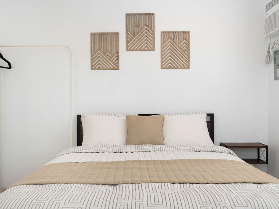A bedroom with a bed, a hanging coat rack, and three wall-mounted decorative panels.
