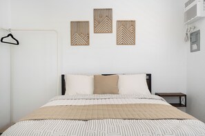 Un dormitorio con una cama, perchero y tres paneles decorativos en la pared.