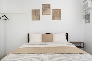 Un dormitorio con una cama, perchero y tres paneles decorativos en la pared.