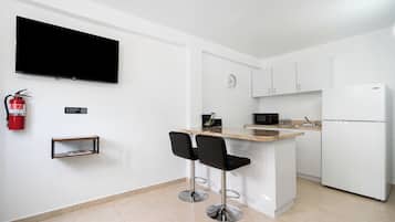 Una cocina moderna con televisión de pantalla plana, un reloj y un refrigerador.