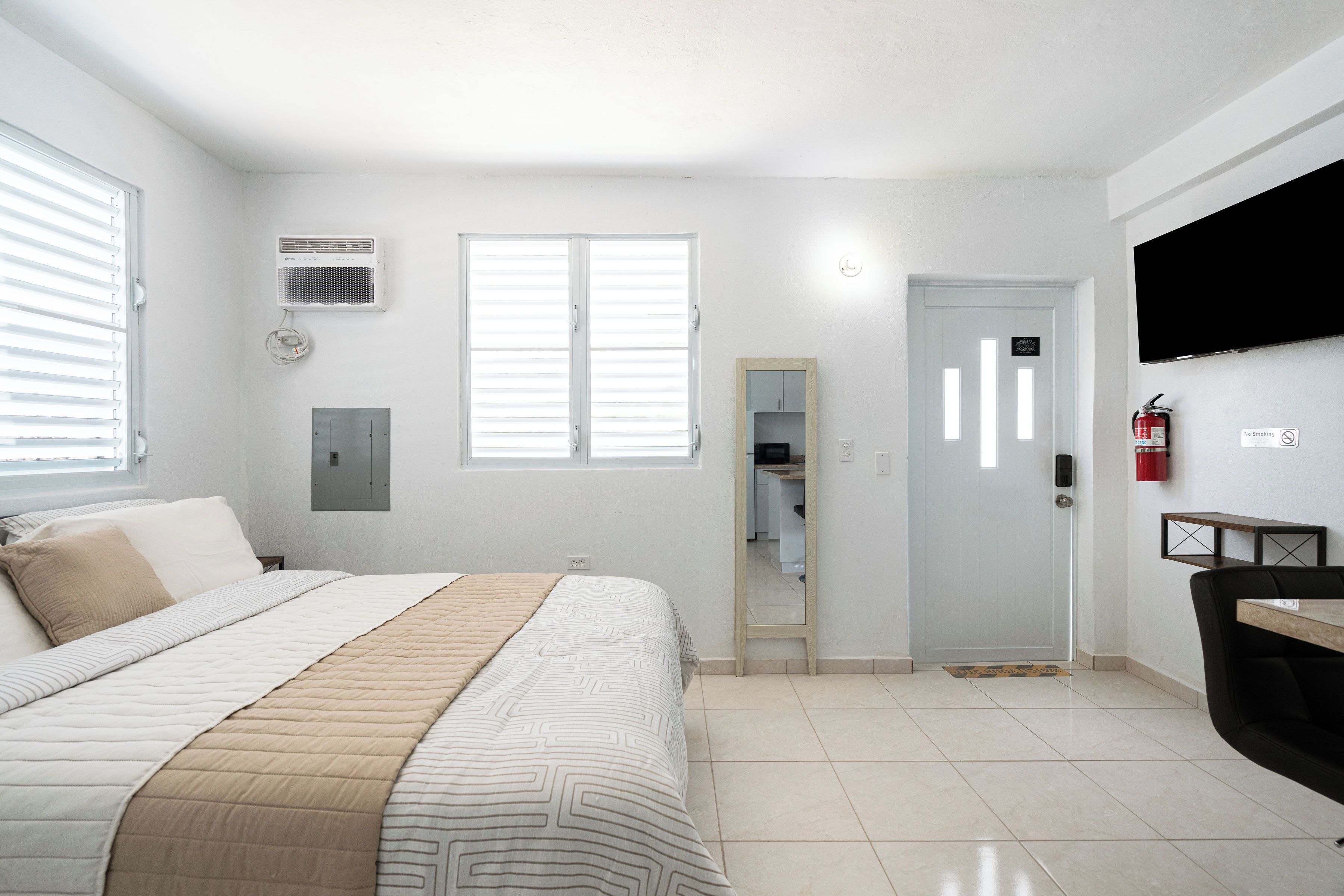 Una habitación de hotel con cama, televisión, puerta y ventana.