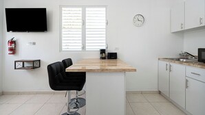 Una cocina moderna con televisor de pantalla plana, cafetera y un taburete de bar.