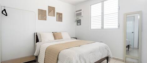 A bedroom with a bed, a wardrobe, a radiator, and a window with blinds.