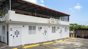 Un edificio con un letrero que dice 'Colmado La Despensa' y un estacionamiento con bordillos amarillos.
