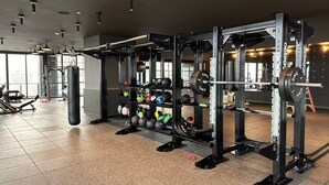 Academia com equipamentos de musculação, esteiras e um saco de pancadas.