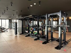 Ein Fitnessstudio mit Krafttrainingsgeräten, Laufbändern und einem Sandsack.