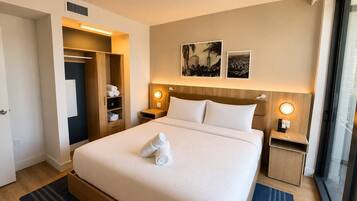 A hotel room with a bed, a wardrobe, a nightstand, and a window.