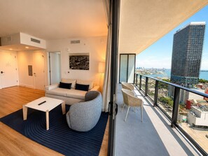 A modern living room with a sofa, coffee table, and a view of the cityscape through large windows. - Gorgeous 1 Bedroom with balcony and amazing views (Miami)