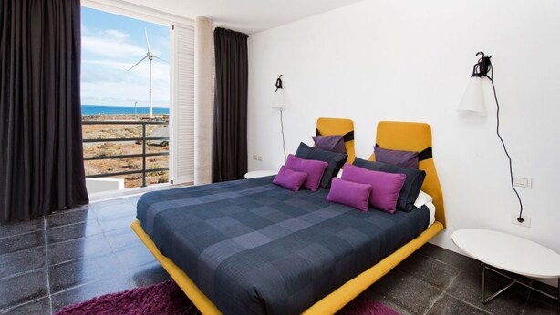 A modern bedroom with a bed, a view of the beach, and a balcony. - Casas Bioclimáticas Iter El Dispositivo (Granadilla de Abona)