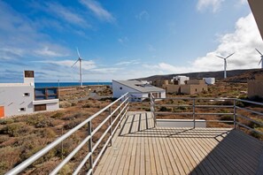 A coastal property with a wooden deck, wind turbines, and modern buildings. - Casas Bioclimáticas Iter El Dispositivo (Granadilla de Abona)