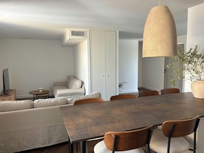 A modern dining area with a large table, chairs, a sofa, and a hanging light fixture. - Garrigue house at the heart of a vineyard estate (Bages)