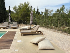 A poolside area with lounge chairs, umbrellas, and a wooden deck. - Garrigue house at the heart of a vineyard estate (Bages)
