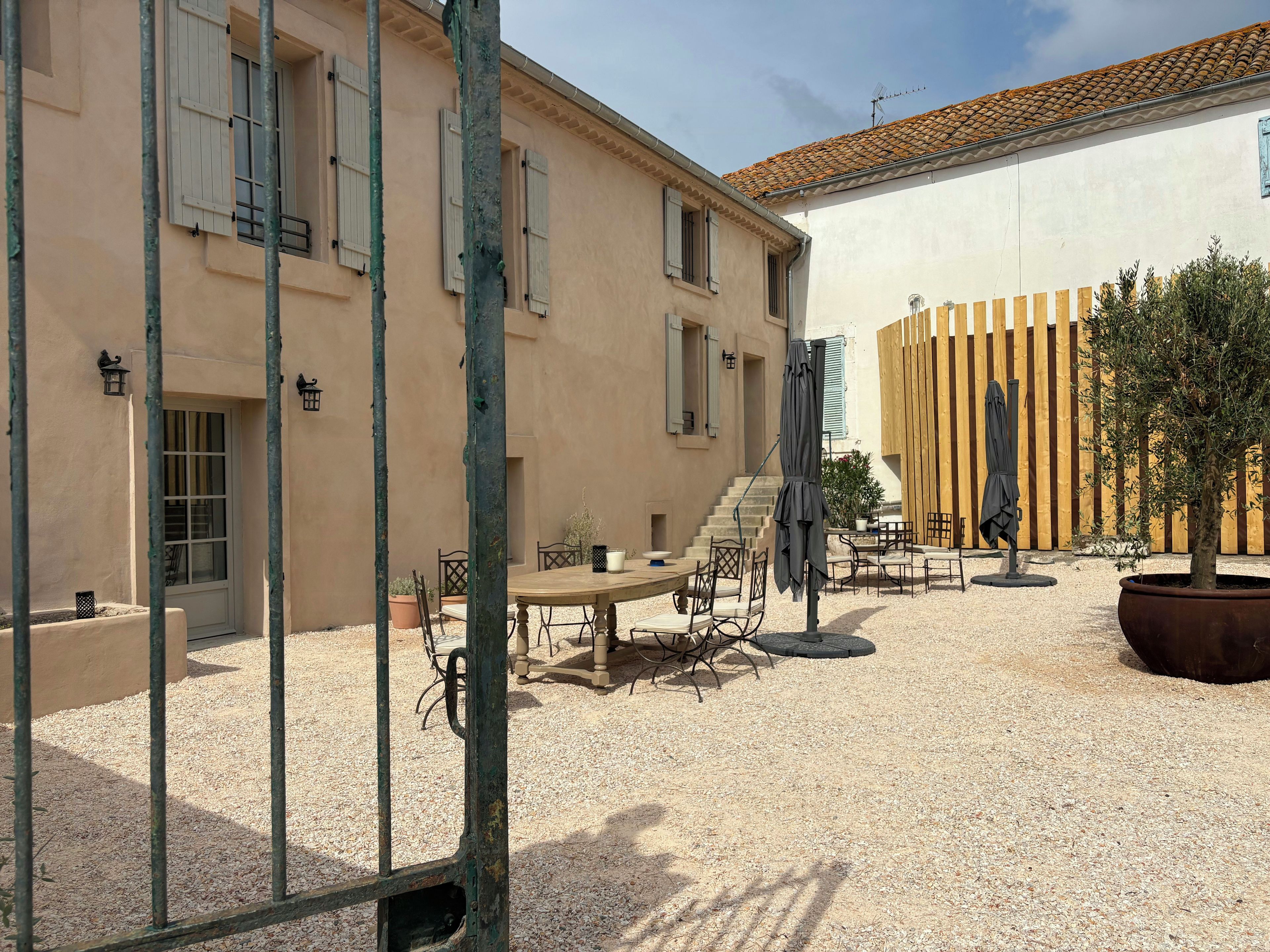 A courtyard with a table and chairs, a potted plant, and a wooden fence.
