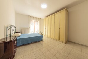 A bedroom with a bed, a wardrobe, a radiator, and a window with curtains. - Andrè Casa Vacanza (Lioni)
