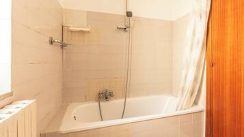 Un baño con bañera, ducha y puerta de madera.