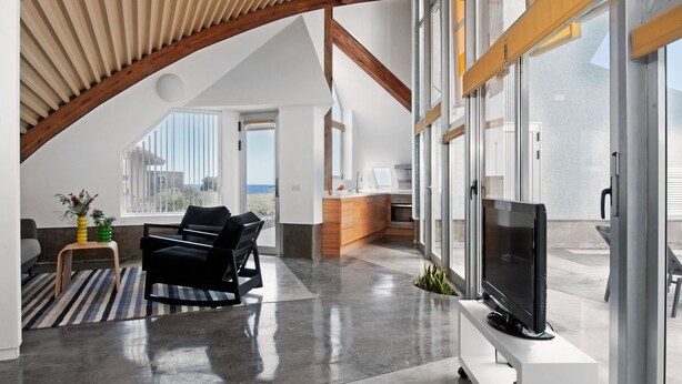 A spacious living area with a high ceiling, a flat-screen TV, and a view of the city. - Casas Bioclimáticas Iter El Cangrejo (Granadilla de Abona)