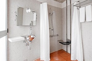 Ein Badezimmer mit Waschbecken, Spiegel, Dusche und weißen Fliesenwänden.