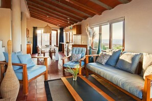 A spacious living area with a sofa, chairs, a coffee table, and a view of the outdoors. - Casas Bioclimáticas Iter La Arcilla (Granadilla de Abona)